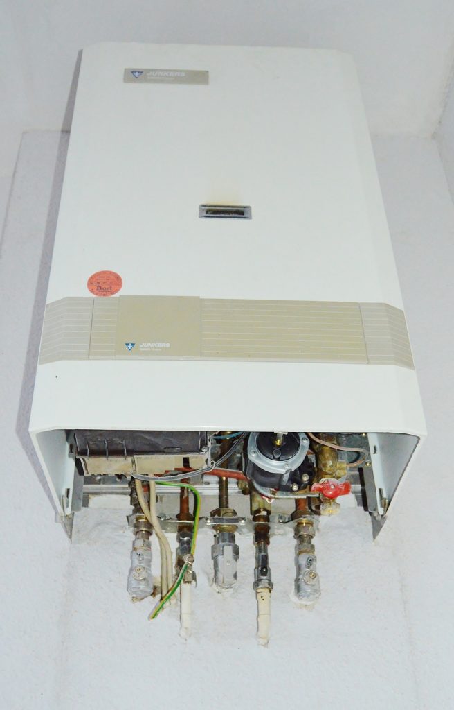 A hot water heater sits on a floor in preparation for it's installation.
